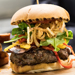 Now This Is A Steak Burger - A one pound patty of the finest 100% certified angus beef, fresh toasted brioche bun, bacon, swiss cheese, onion strings, roasted sweet peppers, horseradish aioli and spicy sriracha ketchup
